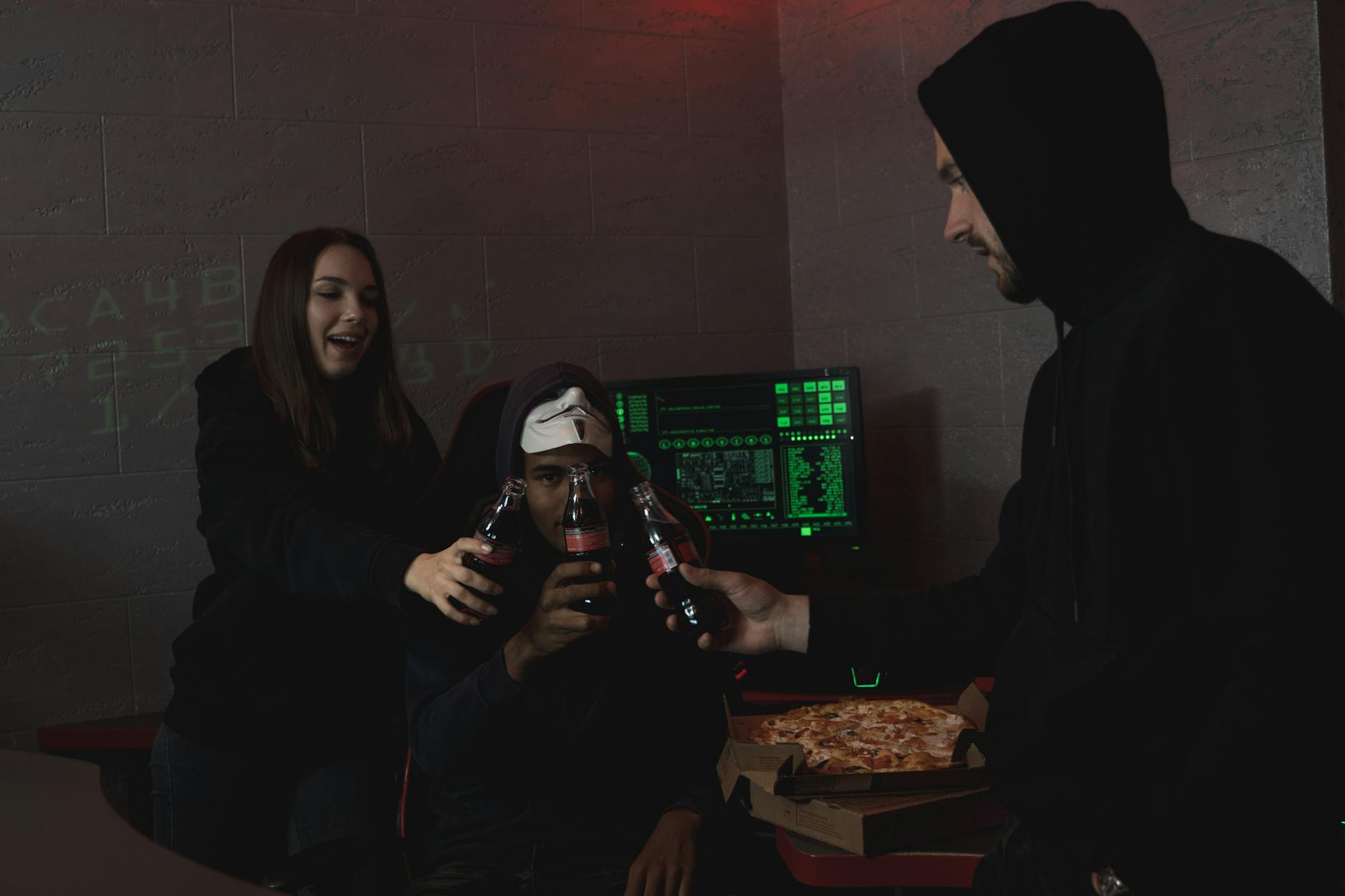 The 2 Hacks That Actually Work - Group of hackers celebrating a successful hack with pizza and soda indoors.